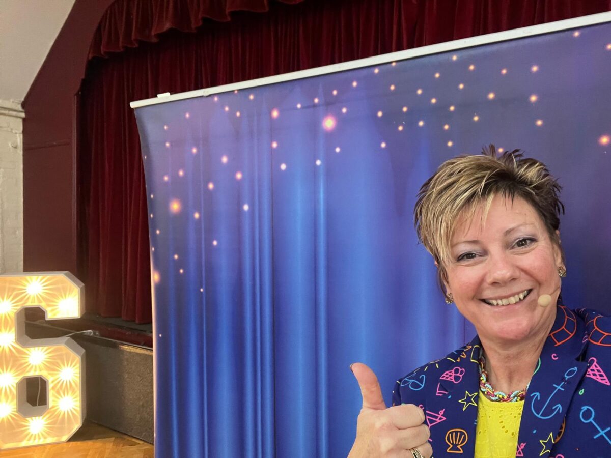 Magic Wanda Kids Entertainer giving a thumbs up in front of a stage